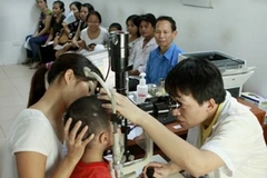 Bác sỹ khám bệnh cho bệnh nhân đau mắt đỏ. (Ảnh: Dương Ngọc/TTXVN)