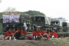 Những người biểu tình "áo đỏ" và đoàn tàu chở trang thiết bị, vũ khí quân sự tại tỉnh Khon Kaen. (Ảnh: Reuters)