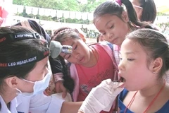 Bác sỹ kiểm tra sức khỏe về răng miệng cho trẻ em. (Ảnh: TTXVN)