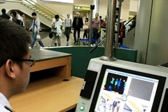 Nhân viên tại sân bay Quốc tế Nội Bài theo dõi thân nhiệt hành khách. (Ảnh: TTXVN)