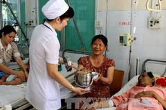 Chuyển suất ăn từ thiện đến tận giường cho bệnh nhân nghèo đang điều trị. (Ảnh: Dương Ngọc/TTXVN)