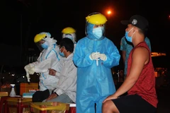 Nhân viên y tế đang lấy mẫu xét nghiệm của người dân tại cảng cá Thọ Quang (Đà Nẵng). (Ảnh: Văn Dũng/TTXVN)