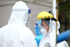 Nhân viên y tế được trang bị đầy đủ quần áo bảo hộ theo đúng quy định phục vụ trạm di động lấy mẫu xét nghiệm. (Ảnh: Minh Quyết/TTXVN)