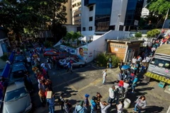 Người dân Venezuela xếp hàng chờ đổi tiền bên ngoài ngân hàng trung ương ở Caracas ngày 16/12. (Nguồn: AFP/TTXVN)