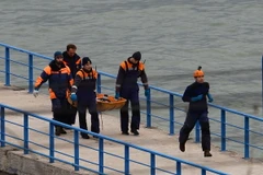 Các nhân viên cứu hộ đưa thi thể nạn nhân vào bờ. (Nguồn: THX/TTXVN)