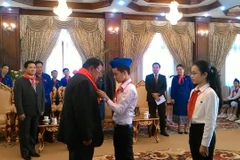 Một thiếu nhi tiêu biểu của Việt Nam đang quàng khăn đỏ cho Tổng Bí thư, Chủ tịch nước Lào Bounnhang Volachith. (Ảnh: Phạm Kiên/Vietnam+)