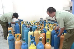 Lực lượng chức năng tỉnh Quảng Bình kiểm tra các bình chứa khí cười vừa bắt giữ. (Ảnh: Đức Thọ/TTXVN)