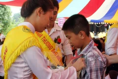 Nghi lễ cài hoa hồng lên ngực áo cho các em học sinh. (Ảnh minh họa: Lan Anh/TTXVN)