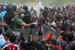 Người di cư chờ đợi làm thủ tục nhập cảnh. (Nguồn: AFP/TTXVN)