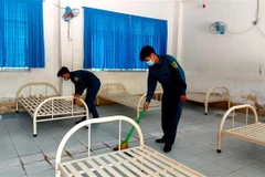 Lực lượng dân quân tự vệ địa phương dọn dẹp điểm cách ly tập trung tại Trường THPT Thốt Nốt (Cần Thơ) chuẩn bị đón người dân vào cách ly. (Ảnh: Thu Hiền/TXVN)