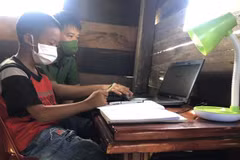Thiếu tá Lê Anh Tuấn, Đội tổng hợp Công an huyện Cư M’Gar hướng dẫn học sinh có hoàn cảnh khó khăn sử dụng laptop do anh trao tặng. (Ảnh: TTXVN phát)