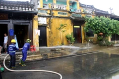 Công nhân Công ty CP Công trình công cộng Hội An tiến hành vệ sinh môi trường, rửa sạch bùn đất trên các tuyến đường tại thành phố Hội An. (Ảnh: Phước Tuệ/TTXVN)