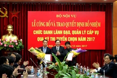 Bộ trưởng Lê Vĩnh Tân tặng hoa chúc mừng ông Trần Trung Kiên và bà Phạm Thu Hằng. (Nguồn: Bộ Nội vụ)