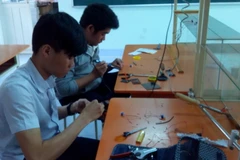 Hai em Thạch và Trung trong phòng thí nghiệm Vật lý của trường. (Ảnh: Hồng Điệp/TTXVN)