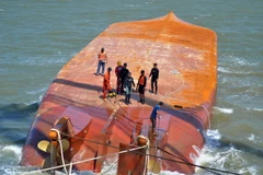 Lực lượng cứu hộ tiến hành móc cáp vào thân tàu Hoàng Phúc 18 để triển khai công tác trục vớt. (Ảnh: TTXVN)