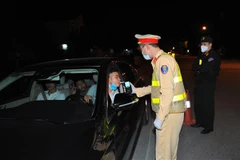 Lực lượng chức năng kiểm tra nồng độ cồn của chủ các phương tiện tham gia giao thông. (Ảnh: Minh Đức/TTXVN)