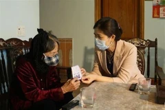 Đại diện Ban chỉ đạo phòng, chống COVID-19 huyện Hà Trung (bên phải) đến nhà cụ Thân để tiếp nhận số tiền cụ ủng hộ. (Ảnh: TTXVN phát)