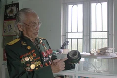 Anh hùng Trần Kim Xuân với những kỉ vật chiến tranh. (Ảnh: Nguyễn Thảo/TTXVN)