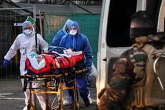 Nhân viên y tế chuyển bệnh nhân nhiễm COVID-19 lên xe cứu thương tới bệnh viện tại Mulhouse, miền đông nước Pháp. (Ảnh: AFP/TTXVN)