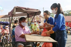 Lực lượng đoàn viên thanh niên hỗ trợ người dân nhận gạo miễn phí từ cây ATM gạo. (Ảnh: Chanh Đa/TTXVN)