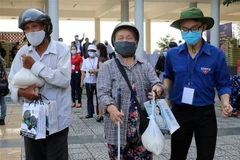 Thanh niên tình nguyện hỗ trợ người khiếm thị đi nhận gạo. (Ảnh: Trần Lê Lâm/TTXVN)