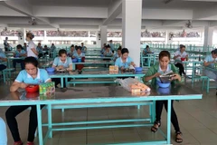 Công nhân ngồi đúng khoảng cách trong nhà ăn để phòng dịch bệnh lây lan. (Ảnh: TTXVN phát)