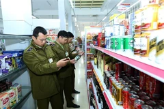 Cán bộ Quản lý thị trường Đội 1 kiểm tra hàng hóa tại Siêu thị Bình An, thành phố Điện Biên Phủ. (Ảnh: Phan Tuấn Anh/TTXVN)