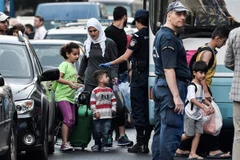 Cảnh sát Hy Lạp áp giải người di cư rời khỏi các khu nhà chiếm dụng bất hợp pháp ở trung tâm thủ đô Athens. (Ảnh: AFP/TTXVN)