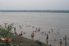 Có đến hàng trăm người, gồm cả người lớn và trẻ nhỏ đến bãi tắm tự phát. (Ảnh: Nguyễn Thắng/TTXVN)