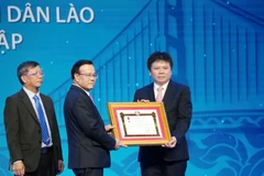 Phó Thủ tướng chính phủ Lào Somdee Duangdee (giữa) trao tặng Huân chương Lao động hạng Nhất cho LaoVietBank. (Ảnh: Xuân Tú/TTXVN)