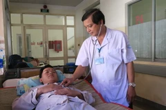 Bác sỹ Nguyễn Thanh Phong, Trưởng khoa Nhiễm D, Bệnh viện Bệnh Nhiệt đới Thành phố Hồ Chí Minh khám bệnh cho bệnh nhân mắc sốt xuất huyết. (Ảnh: Đinh Hằng/TTXVN)