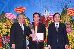 Đại diện Hội đồng chức danh giáo sư Nhà nước trao chứng nhận cho các tân giáo sư, phó giáo sư. (Ảnh: Quý Trung/TTXVN)