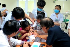 Các giáo sư, bác sỹ khám, điều trị và phẫu thuật miễn phí cho trẻ em bị sứt môi, hở hàm ếch, sẹo xấu ở mũi, khe hở ngang mặt. (Ảnh: Tường Vi/TTXVN)