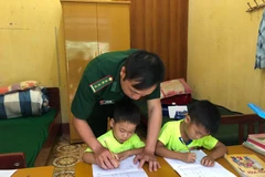 Cán bộ đồn biên phòng Xuân Trường dạy các "con nuôi" học bài. (Ảnh: Chu Hiệu/TTXVN)