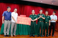 Đại diện Binh đoàn 11 thuộc Bộ Quốc phòng Việt Nam, trao số tiền ủng hộ 100 triệu kíp (hơn 11.000 USD). (Ảnh: Phạm Kiên/TTXVN)