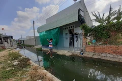 Để vào được nhà, người dân ấp Phước Lâm phải kê các hòn đá, xe máy phải gửi nhà hàng xóm. Ảnh: Hoàng Nhị - TTXVN