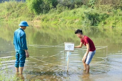 Lực lượng dân quân quây chắn và đặt biển cảnh báo tại khu vực phát hiện quả bom. (Ảnh: Xuân Tư/TTXVN)