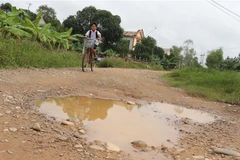 Mặt đường dở dang của dự án có các ổ voi, ổ gà tạo thành hố sâu rất dễ gây tai nạn. (Ảnh: Nguyên Lý/TTXVN) 