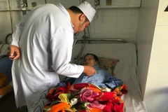 Bác sỹ thăm khám cho bệnh nhân Nguyễn Thị Bạc sau phẫu thuật. (Nguồn: TTXVN) 