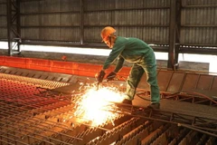 Công nhân Nhà máy cán thép Thái Trung, Công ty Cổ phần gang thép Thái Nguyên lấy mẫu thép cán mới ra lò. (Ảnh: Hoàng Nguyên/TTXVN) 