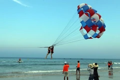 Khách du lịch tham gia trò chơi canô kéo dù tại biển Phạm Văn Đồng (Đà Nẵng). (Ảnh: Trần Lê Lâm/TTXVN) 