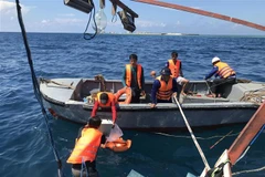 Lực lượng cứu hộ di chuyển các vật dụng thiết yếu trên tàu cá BĐ 99137 TS xuống xuồng cứu nạn. (Ảnh: Huỳnh Ngọc Sơn/TTXVN) 