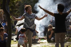 Người lớn nướng thịt trong công viên mừng ngày Quốc khánh đánh dấu sự độc lập của đất nước trong khi trẻ chạy xung quanh.