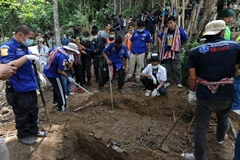 Lực lượng chức năng khai quật thi thể các nạn nhân trong ngôi mộ tập thể ở Thái Lan. (Nguồn: AFP/TTXVN)