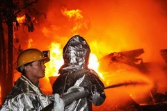 Lực lượng phòng cháy chữa cháy nỗ lực dập lửa. (Ảnh: Văn Đức/Vietnam+)