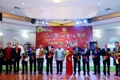 Đồng chí Saysomphone Phomvihane (giữa), Ủy viên Bộ Chính, Chủ tịch Mặt trận Lào Xây dựng Đất nước, cùng các quan khách chụp ảnh lưu niệm với các thành viên Ban Chấp hành Tổng hội Người Việt Nam tại Lào. (Ảnh: Phạm Kiên/TTXVN)