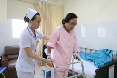 Bệnh nhân Trần Thị Kim Anh (bị gãy chân) đang được hỗ trợ vận động tại Bệnh viện Sài Gòn ITO Phú Nhuận. (Ảnh: Đinh Hằng/TTXVN) 