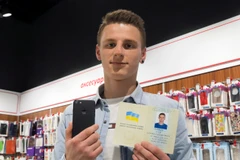 "iPhone 7" bên chiếc iPhone 7 của mình và cuốn hộ chiếu đã đổi tên tại một cửa hàng điện tử ở Kiev, Ukraine. (Nguồn: AP)