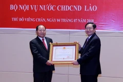 Bộ trưởng Bộ Nội vụ Việt Nam Lê Vĩnh Tân trao Quyết định tặng Huân chương Độc lập hạng Nhì của Nhà nước Việt Nam cho Bộ trưởng Nội vụ Lào Khamman Sonvileuth. (Ảnh: Phạm Kiên/TTXVN)