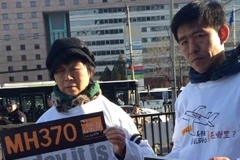 Thân nhân hành khách người Malaysia và Trung Quốc nắm tay nhau tổ chức hoạt động tưởng niệm một năm ngày MH370 mất tích. (Nguồn: QQ)